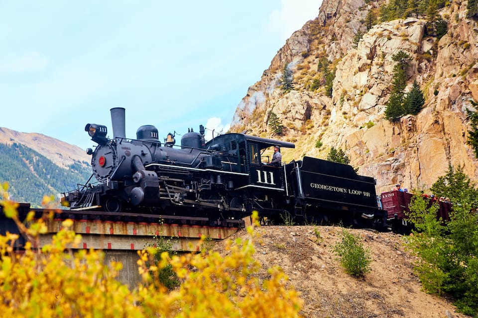 A black steam locomotive with the number 111 on a mountain railway track.