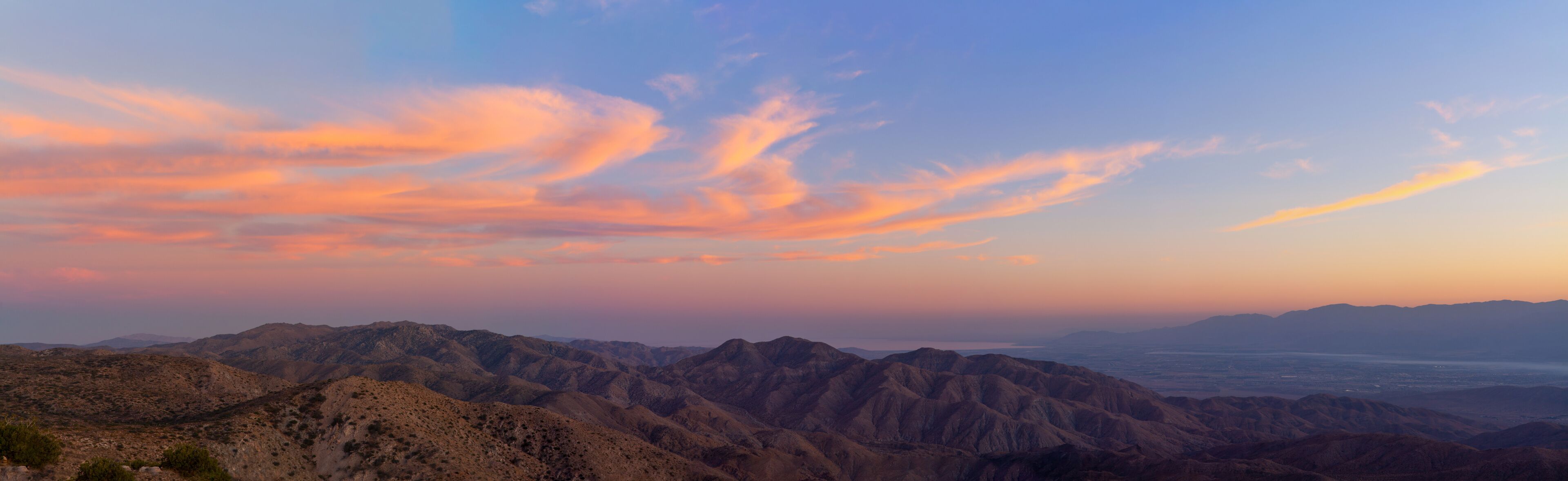 A mountainous landscape with a sunset sky.