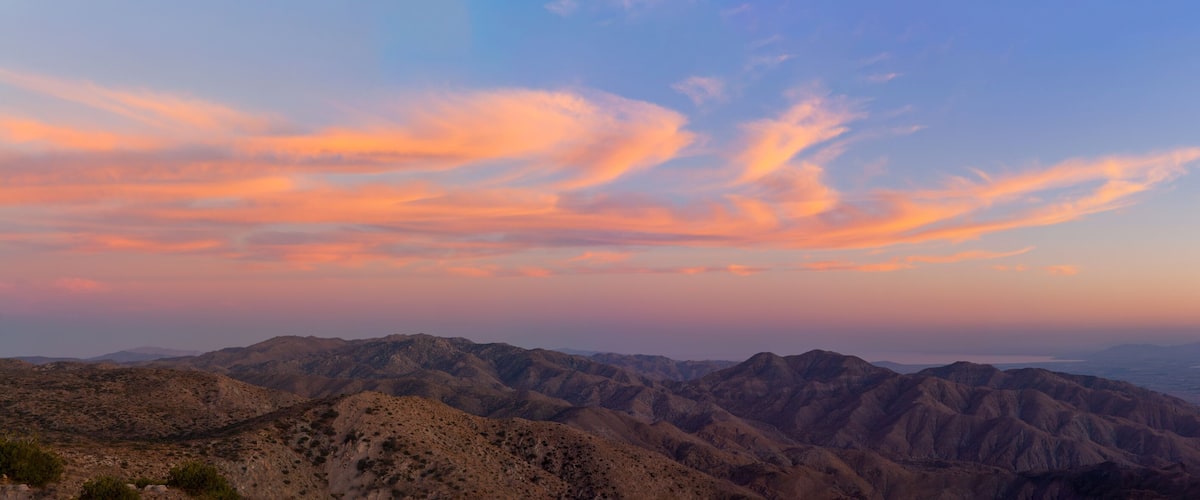 A mountainous landscape with a sunset sky.