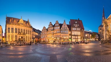 A historic European square with cobblestone pavement, ornate buildings, and a prominent church steeple.
