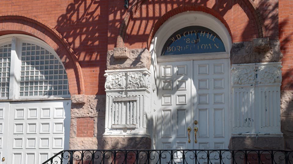 A historic building with arched windows and a white door with a sign above it.