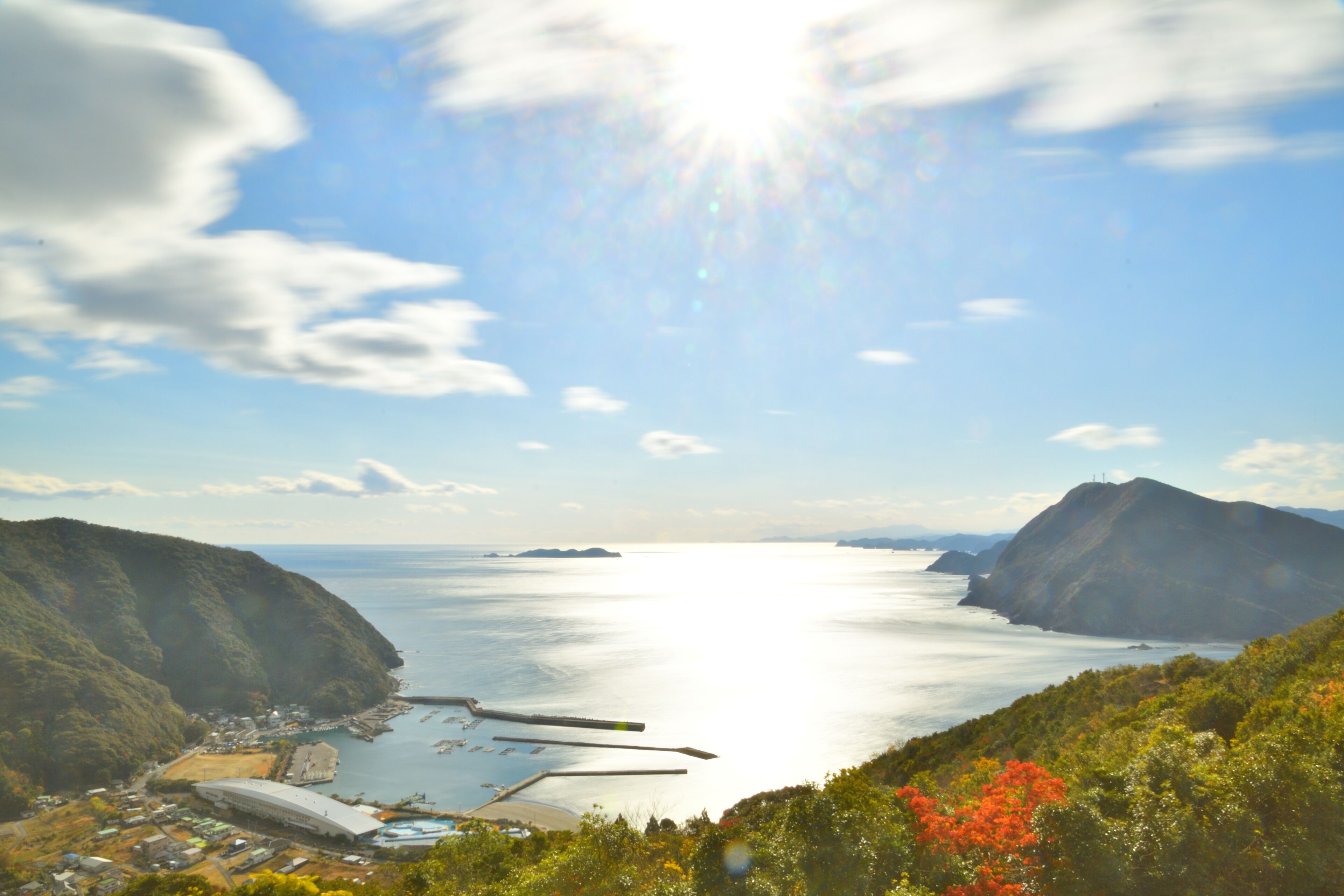 A coastal landscape with a large body of water, hills, and a stadium.