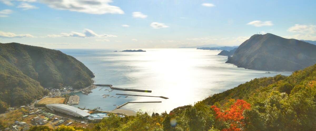 A coastal landscape with a large body of water, hills, and a stadium.