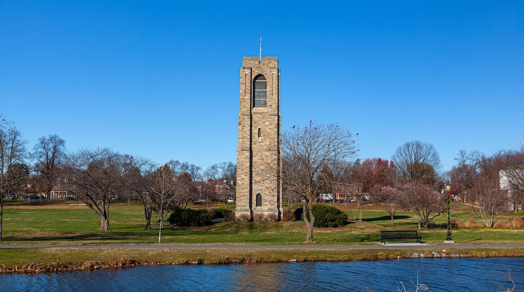 Baker Park, a city park by Carrol Creek with large open meadows, trees, walking and cycling paths and the famous historic tower and carillon. Image shows Frederick cityscape with the river.
