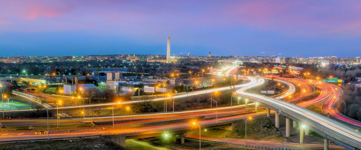 A cityscape with a prominent monument, multiple highways, and illuminated buildings.
