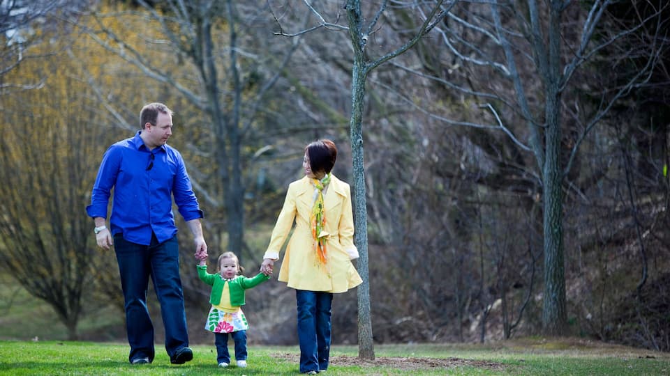 A family walking in a park with trees and grass.