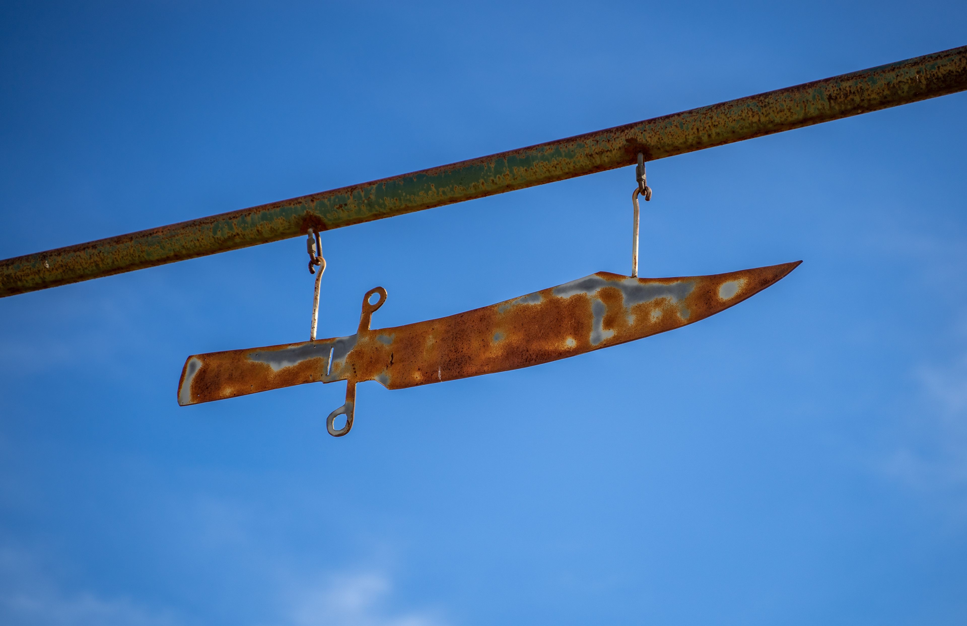 Metal Rustic Bowie Knife Statue Hanging Banner With Blue Sky in Bowie, Texas