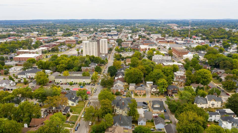 A cityscape with a mix of residential and commercial buildings, surrounded by greenery.
