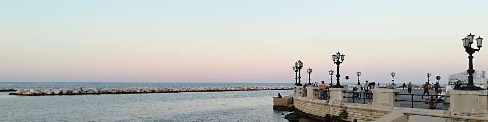 A coastal promenade with stone barriers and street lamps.