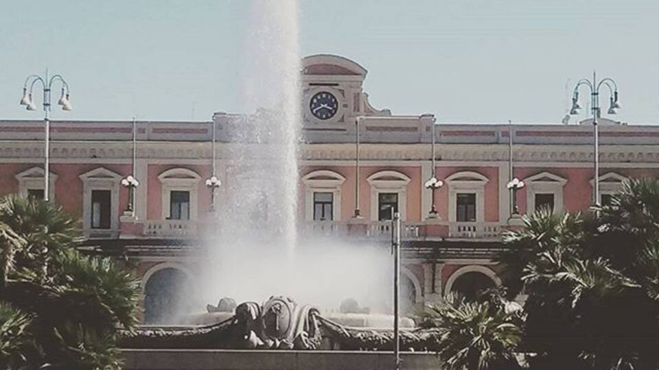 Una fuente frente a un edificio con una torre de reloj.
