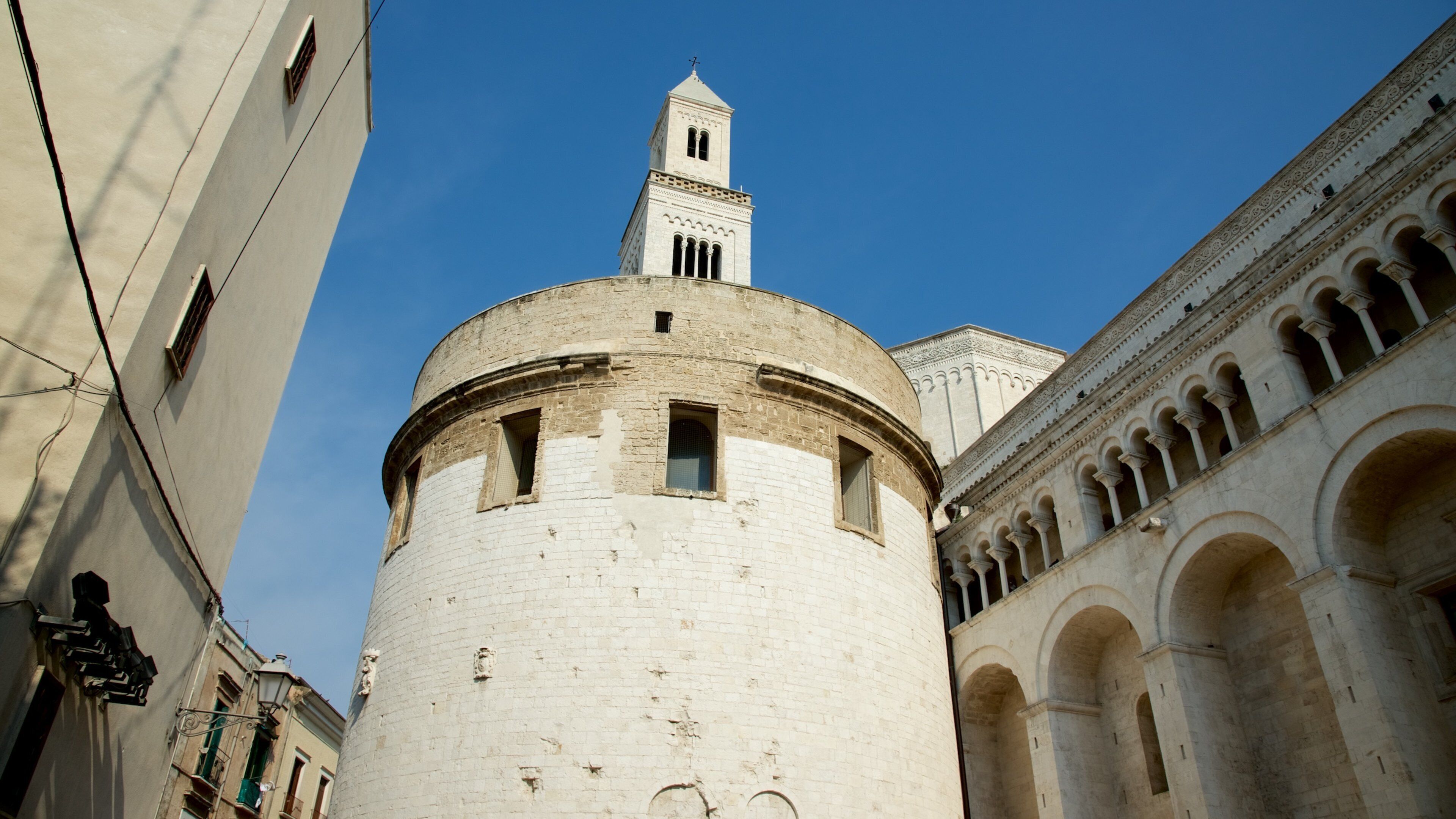 A historic tower with a bell tower, surrounded by classical architecture and a clear blue sky.