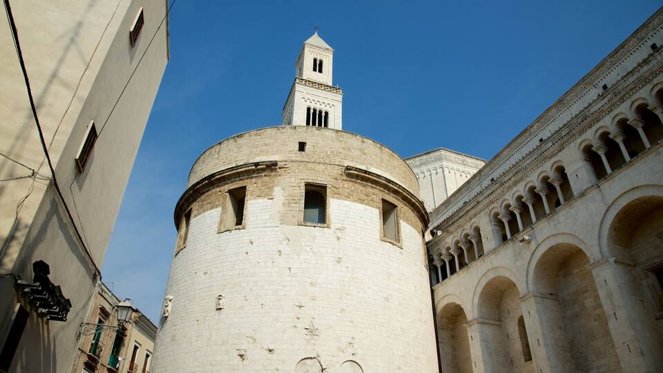 A historic tower with a bell tower, surrounded by classical architecture and a clear blue sky.