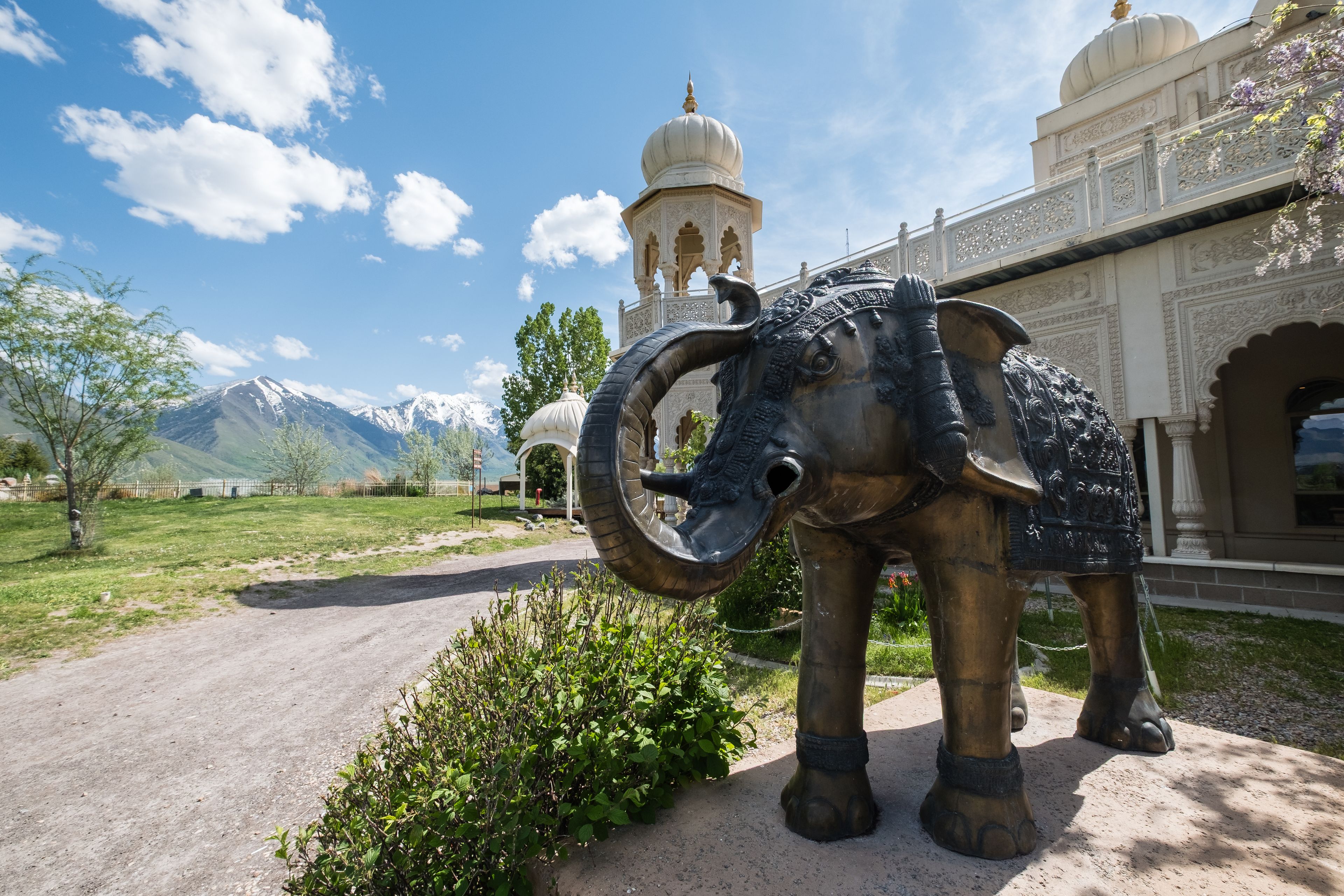 A large elephant statue, a domed building, and mountains in the background.