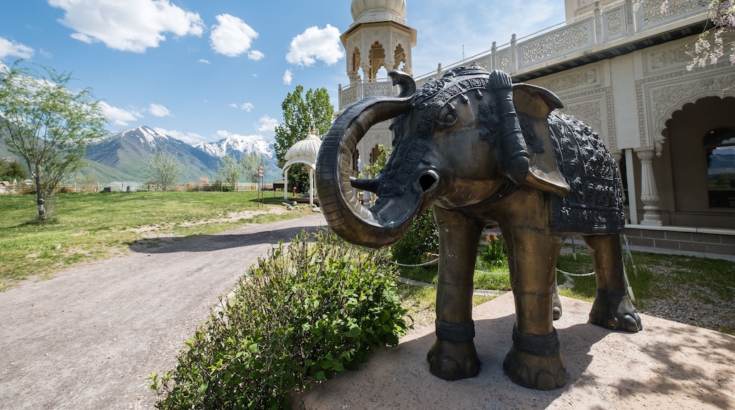 A large elephant statue, a domed building, and mountains in the background.