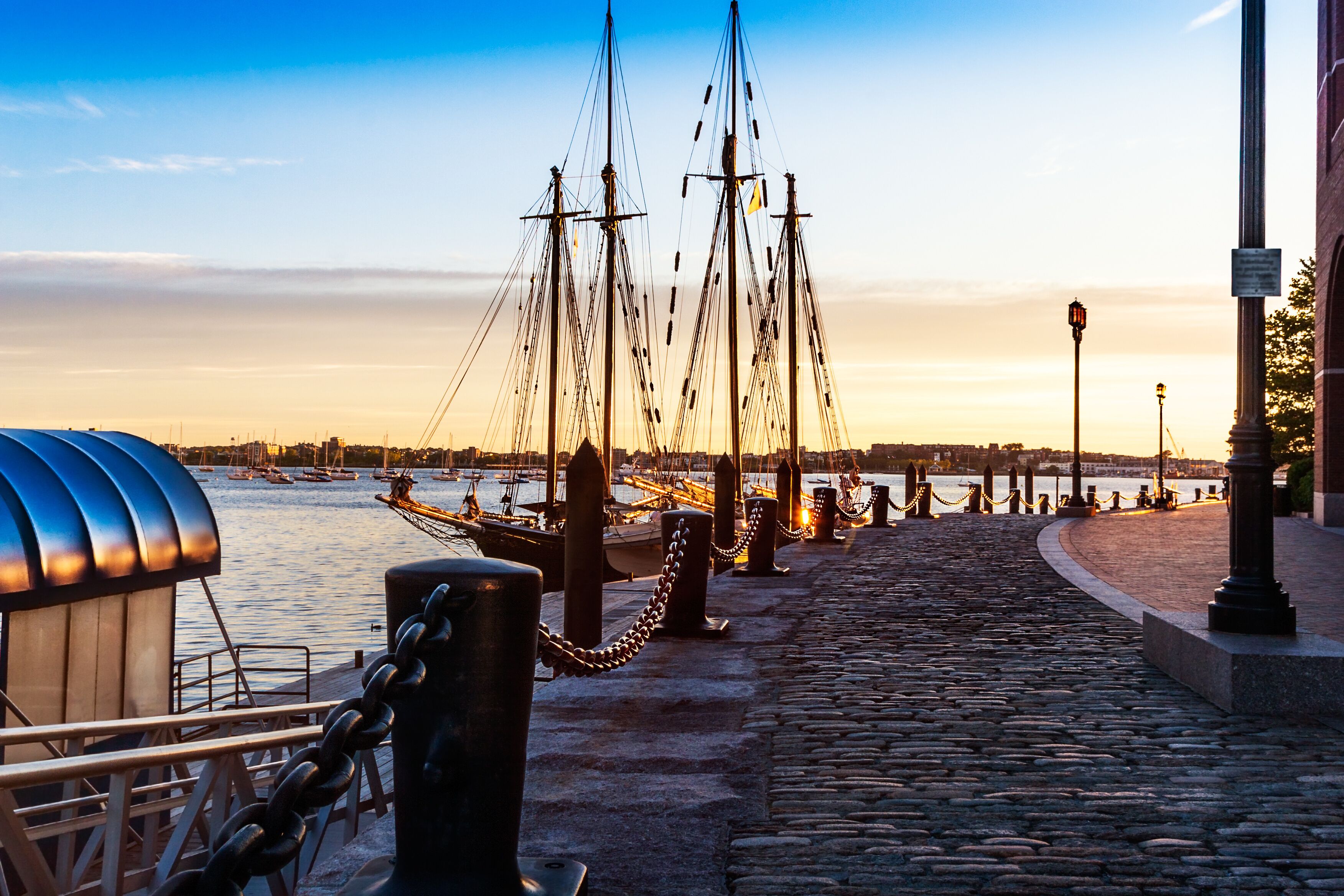 First light catches the bollards and heavy chains by the moored tall ships in Boston Harbor