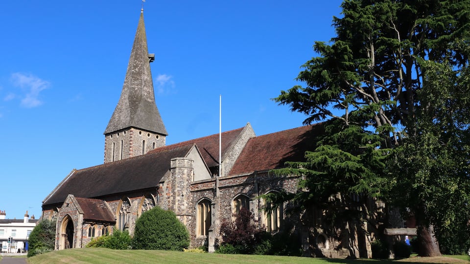 A historic church with a prominent steeple and a well-maintained lawn.