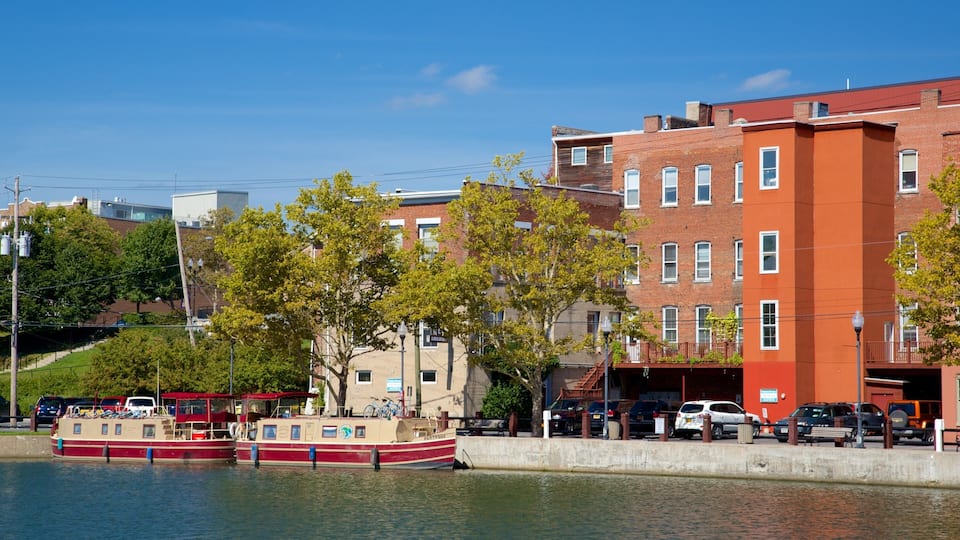 A waterfront with a red and white boat docked, surrounded by buildings and trees.