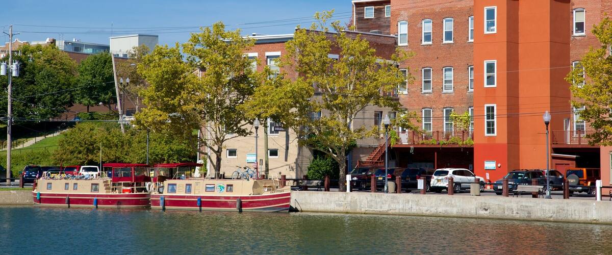 A waterfront with a red and white boat docked, surrounded by buildings and trees.