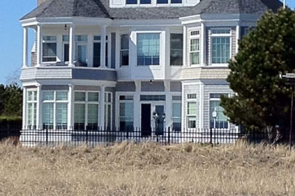 A large, two-story house with a wrap-around porch and a chimney.