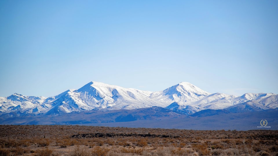 A snow-capped mountain range with a clear blue sky.