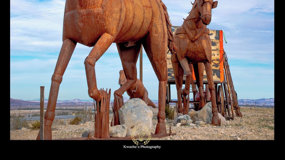 A large rusted horse statue in a desert landscape.