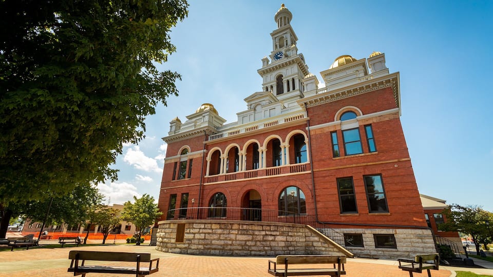 A historic building with a clock tower, arched windows, and a stone staircase.