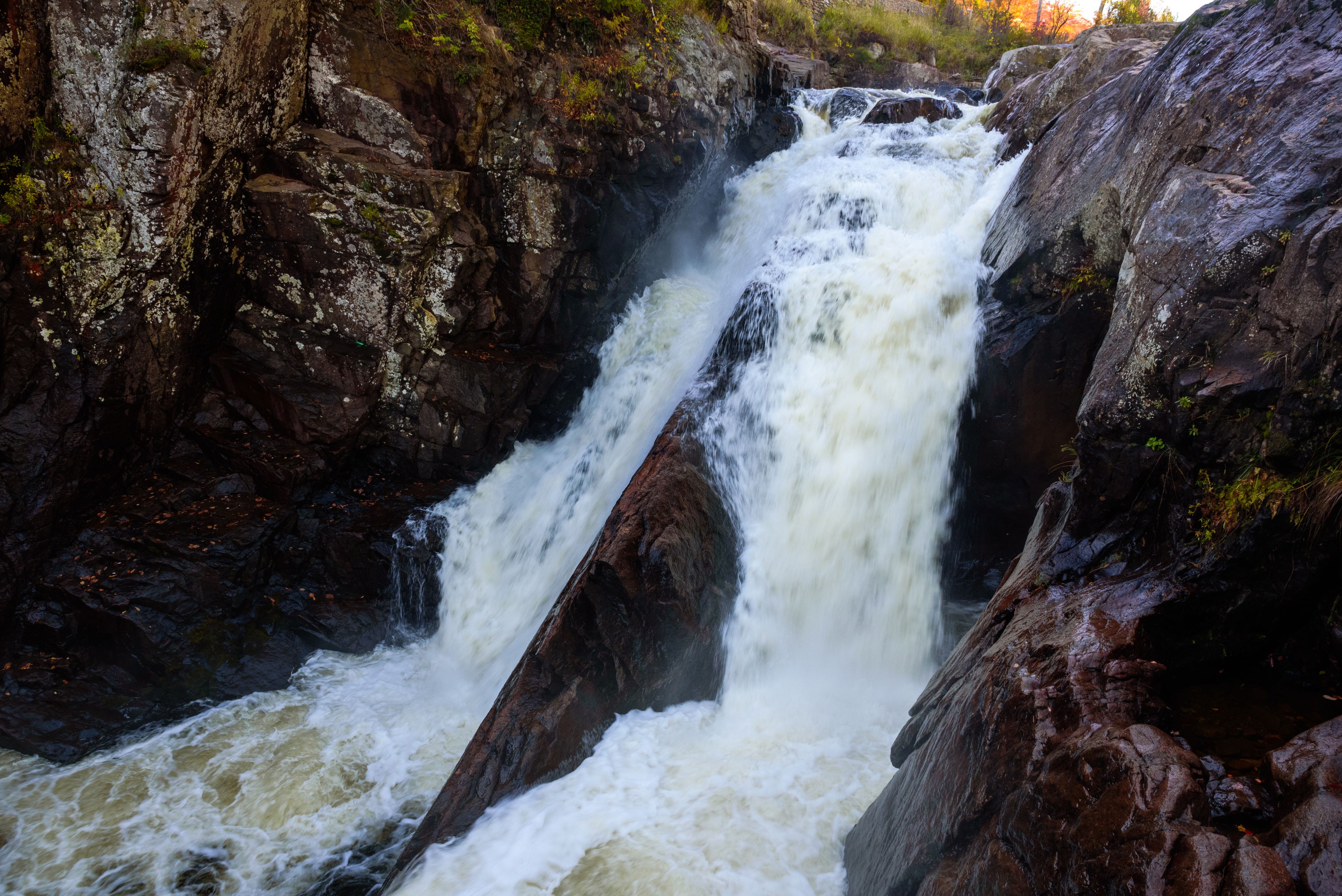 A powerful waterfall cascading over rocky terrain with moss-covered stones.