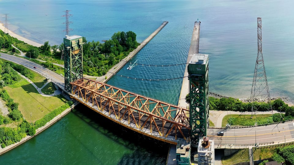 A large steel bridge over a river with a beach and roads on either side.