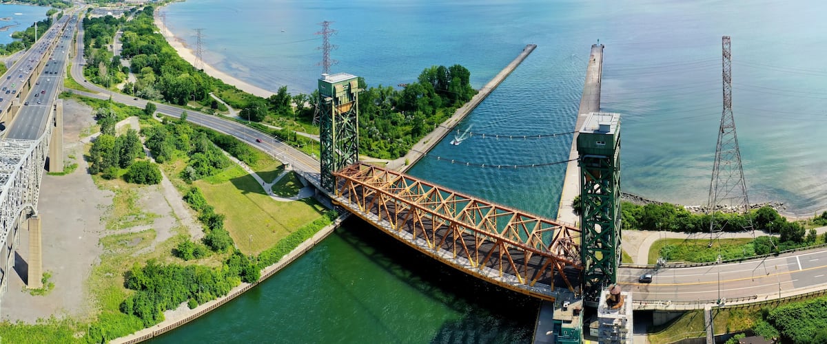 A large steel bridge over a river with a beach and roads on either side.