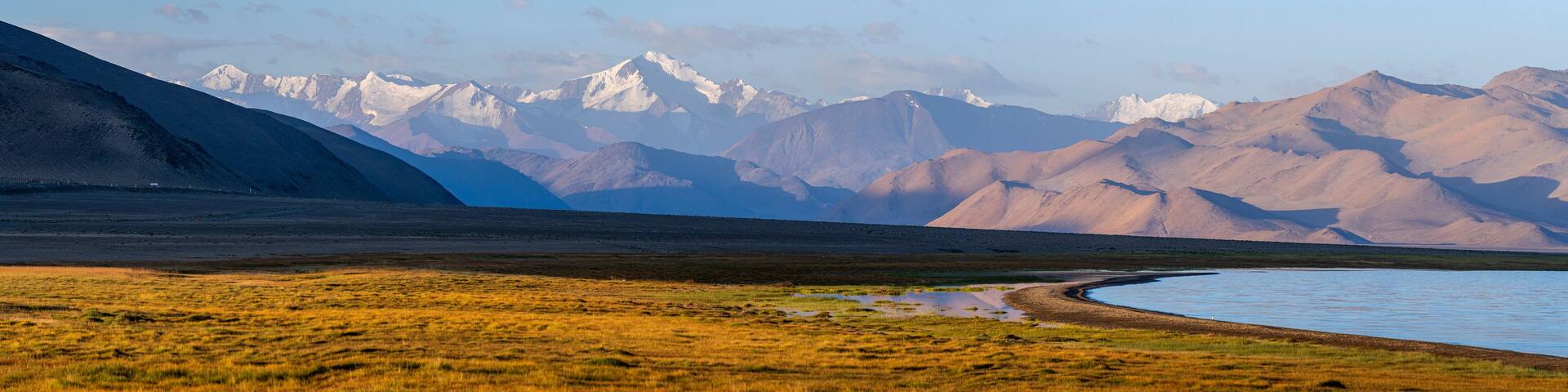 Sunrise landscape panorama
on Karakul lakeshore, with Muzkol snowcapped mountain range, Murghab, Gorno-Badakhshan, Tajikistan Pamir