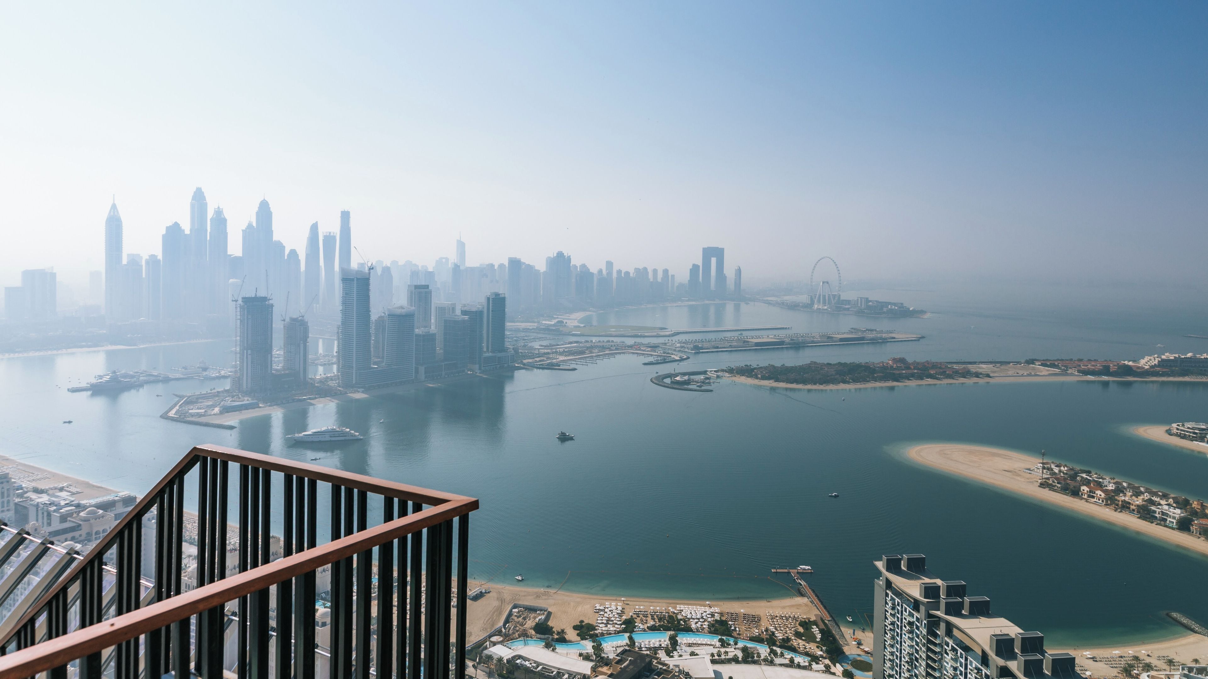 A coastal cityscape with high-rise buildings, a marina, and a beach.