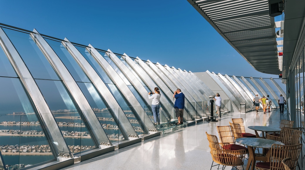 A glass observation deck with a panoramic view of a coastal city.
