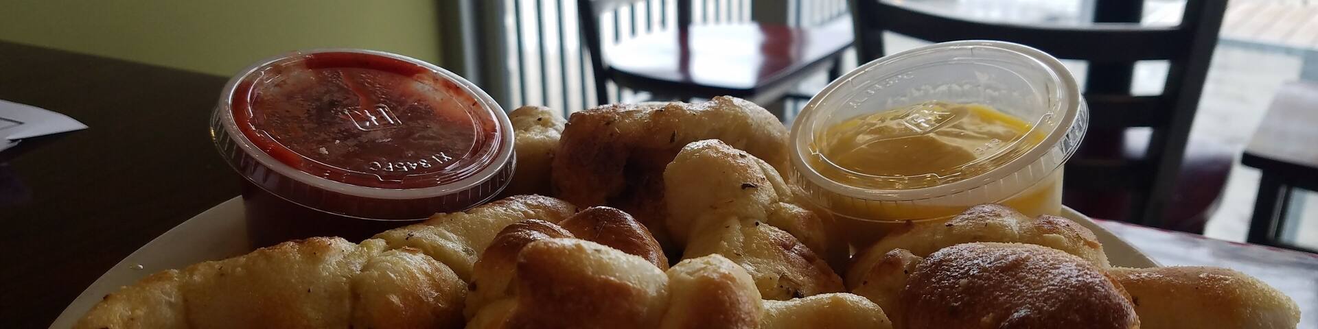 A plate of fried dough with dipping sauces.