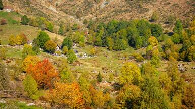 A valley with a small village surrounded by hills and autumn-colored trees.