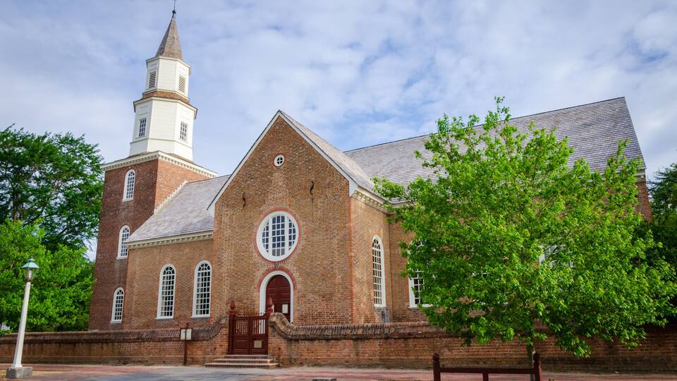 A historic brick church with a steeple and a large circular window.