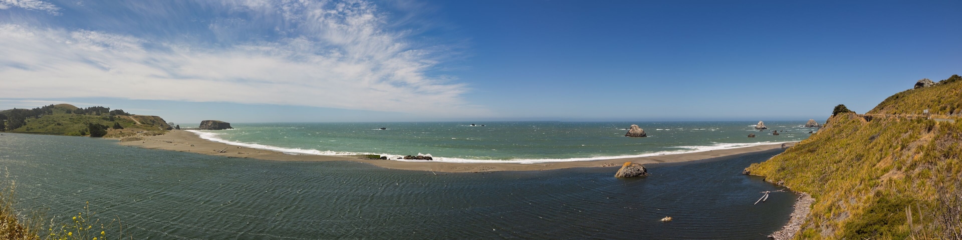 Eine Küstenlandschaft mit Sandstrand, ruhiger See und Felsformationen.