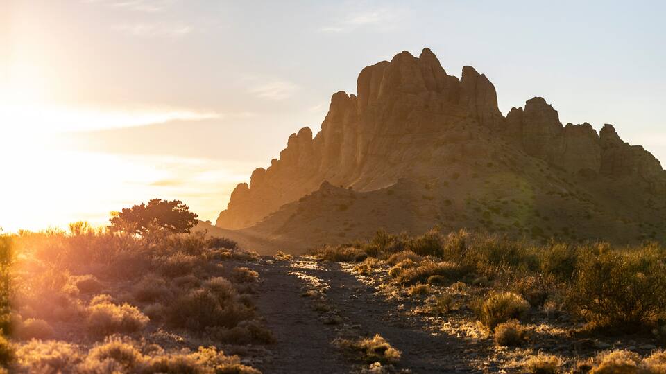 A rocky mountain range with a dirt path leading up to it.