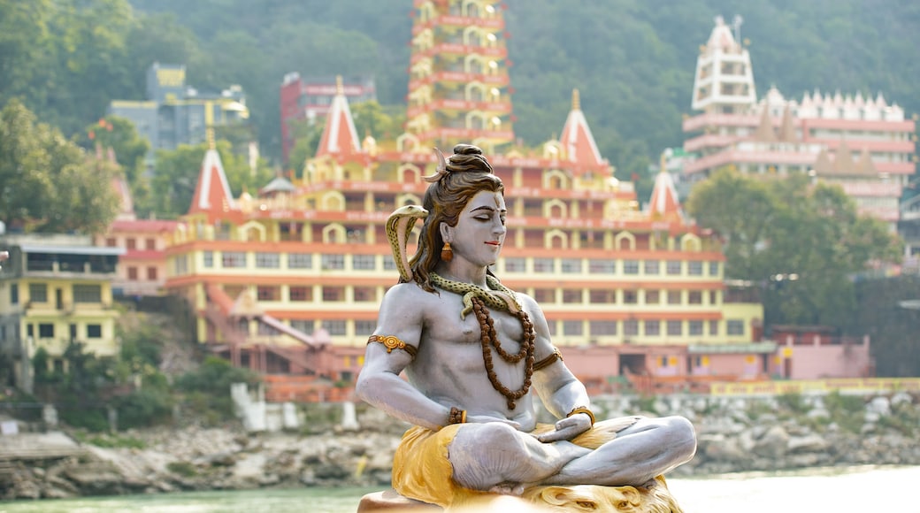 Stunning view of the statue of sitting Lord Shiva on the riverbank of the Ganges river. Blurred Trimbakeshwar Temple in the background. Rishikesh, Uttarakhand, India.