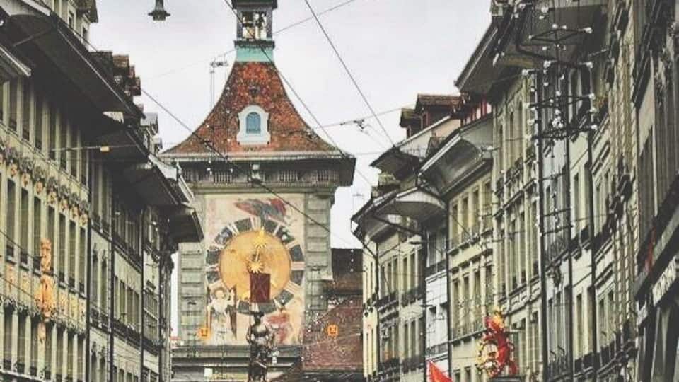 Una calle con edificios, una torre del reloj y una bandera.