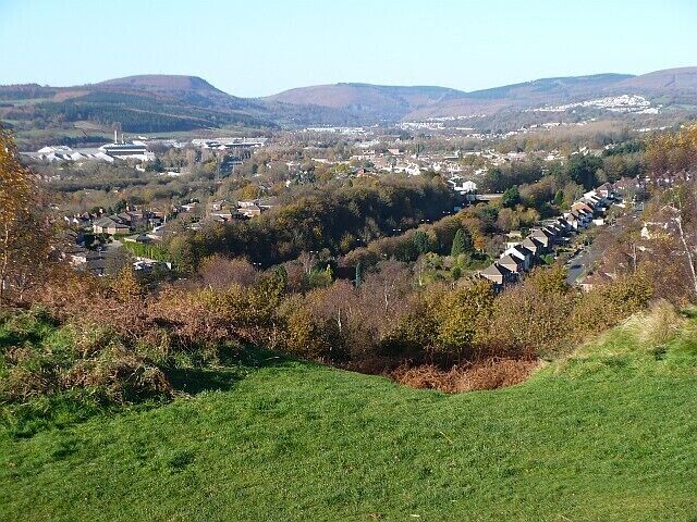 Un valle con una hilera de casas, una colina y un pueblo lejano.