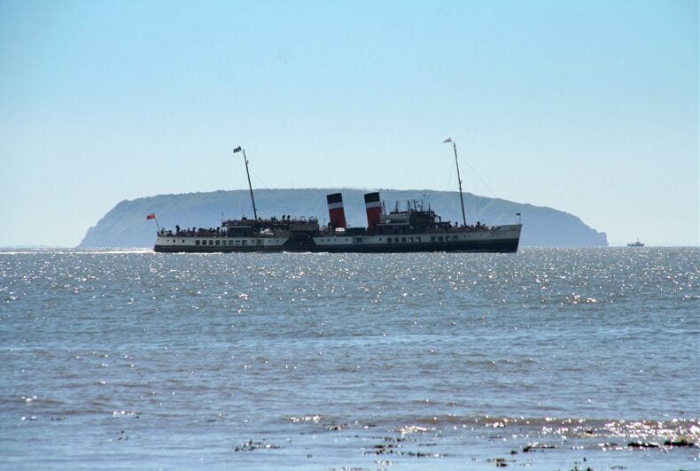 Un barco grande con dos altos mástiles navegando en aguas tranquilas.