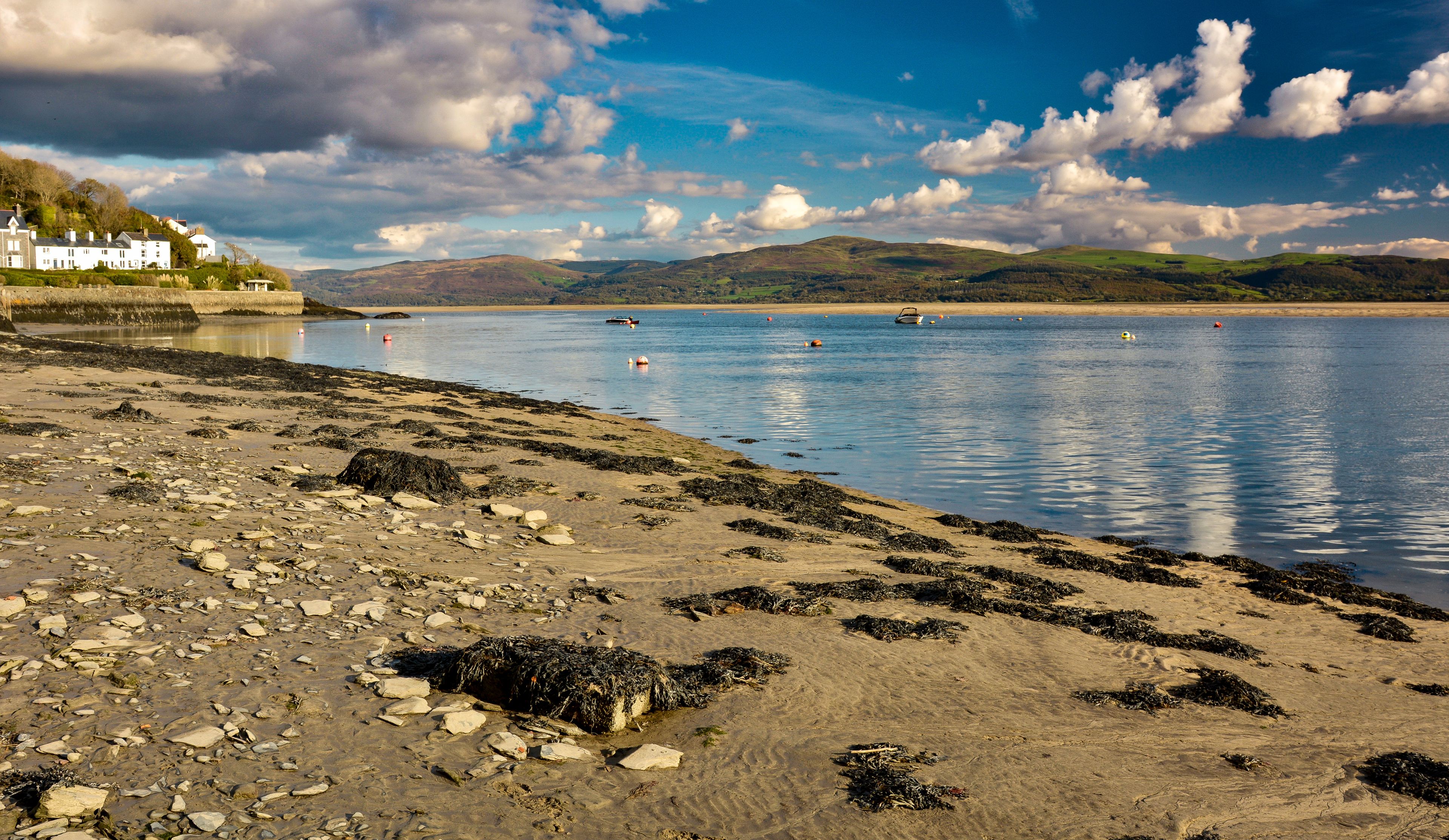 A coastal landscape with a sandy beach, rocky shore, and a calm body of water.