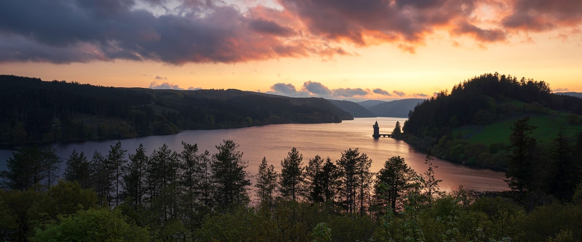 Lake Vyrnwy, located in mid Wales, an area of outstanding natural beauty, at sunset. The orange sky is reflected in the calm water of the lake