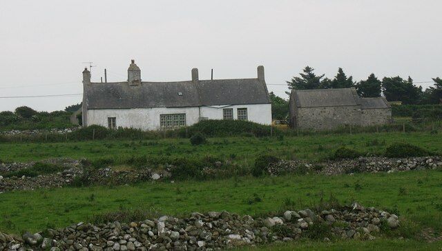 Una casa blanca con techo gris en un entorno rural.