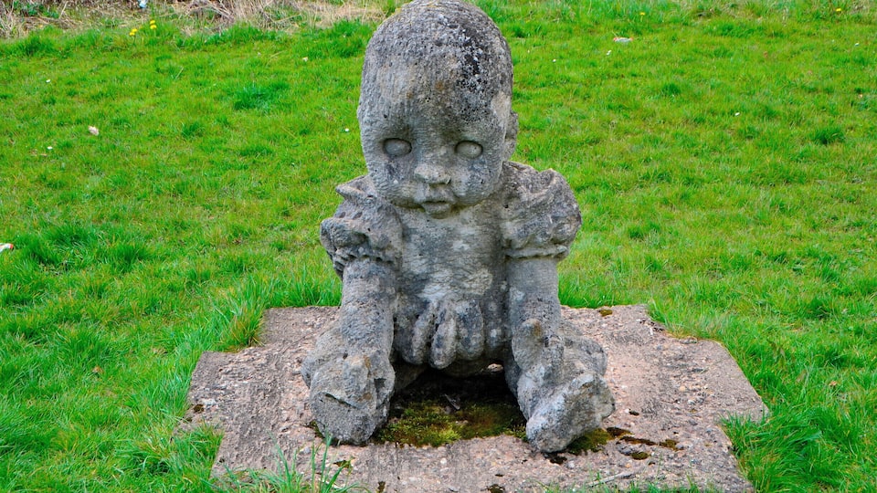 Sculptor Robert Kennedy.
Six separate small upright works set on stone bases; two boxing gloves, two dolls, cherub and a skull. Information from Festival Park: 'The works were carved away from site during 1991. They are made to operate as conventional garden ornamentation, within a constructed garden. The boxing gloves are there to depict some of their associated aspects, such as maleness and competition. The dolls depict something of how an image is idealised for mass consumption, becoming a distortion of the human figure. Both the gloves and the dolls can be seen as gendering devices through role play. The cherub and skull are life and death charms. Each of these suggests ways in which we adopt roles in society. What we really are is never as clear cut as what these images suggest.'
Borderline was supported by Garden Festival Wales and Chapter Arts Centre. 'The sculptor, Robert Kennedy, felt that the Garden Festival was a huge, themed social event in itself. He wanted to create a themed garden within it, something social, commenting to some extent on the diversity of culture within real society.'
A number of sculptures were commissioned for the Garden Festival of Wales in 1991/2 and some works remain on site.