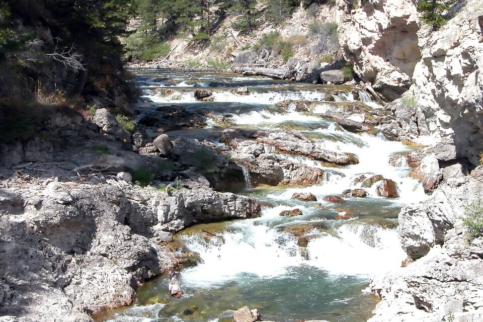 A rocky river with clear water flowing through a canyon.
