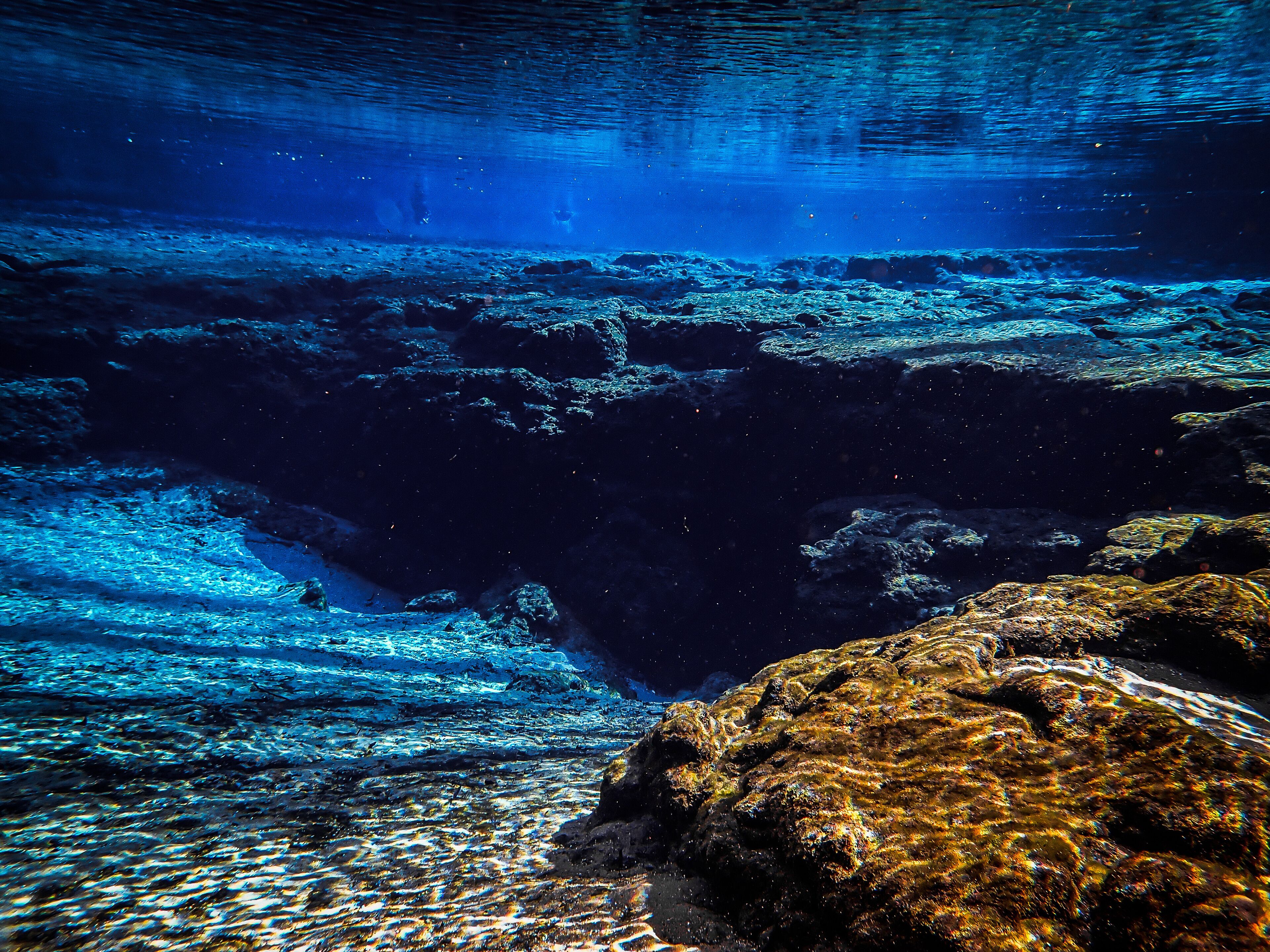 Blue waters of the spring basin drop down to the rocky cavern entrance at Ginnie Ballroom, Ginnie Springs, Florida
