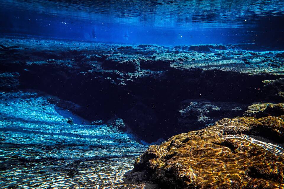 An underwater scene with rocky formations and clear water.