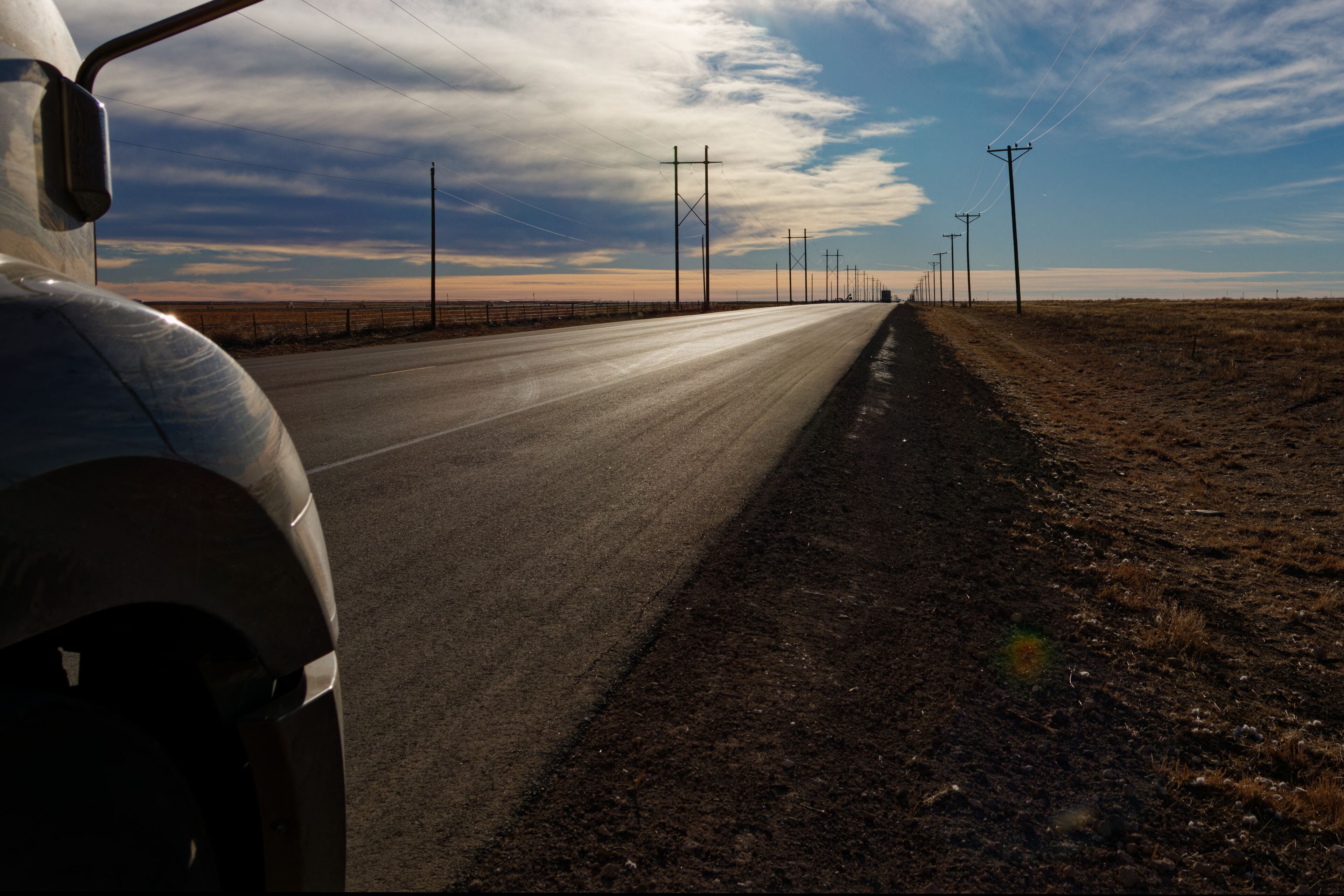 The nose of a semi truck stands shadow as the sun sets over US-54 in Dalhart, Texas