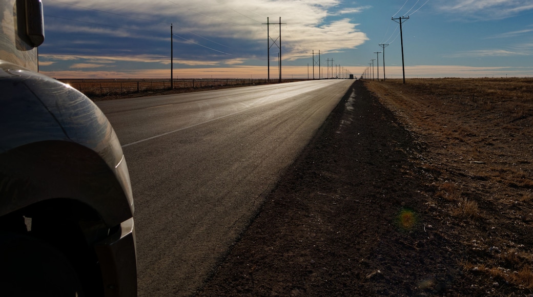 The nose of a semi truck stands shadow as the sun sets over US-54 in Dalhart, Texas